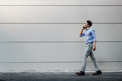 Full length of man photographing while standing on wall