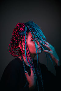 Portrait of young woman wearing mask against black background