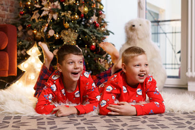 Christmas at home. children lie under the tree. little boys in red pajamas.