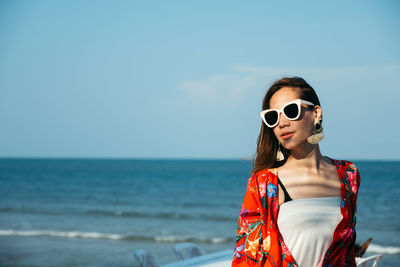 Woman wearing sunglasses at beach against sky