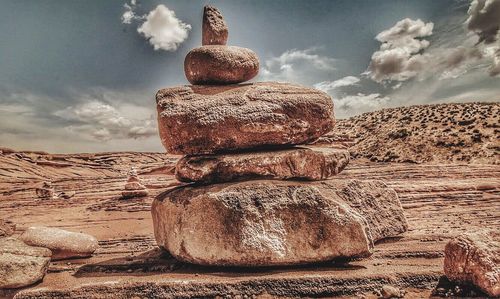 Stack of rocks on landscape against sky
