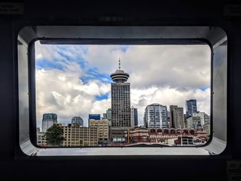 Buildings against sky seen through glass window