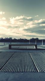 Empty footpath in city against sky during sunset