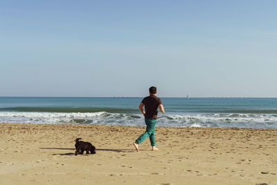 Rear view of man running to the sea against sky