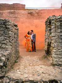 People standing by stone wall