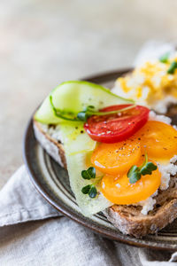 Open sandwiches with cucumber, tomatoes, cream cheese and scrambled egg on stone background.