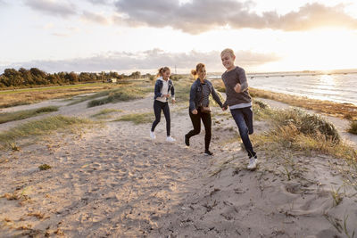 Smiling mother and children playing at beach during weekend