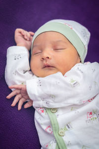 Newborn baby isolated sleeping in white cloth with purple background from different angle