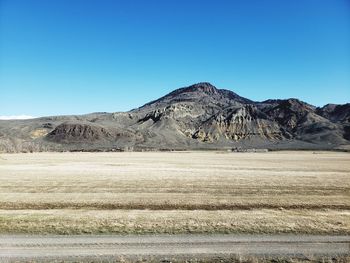 Scenic view of arid landscape against clear blue sky