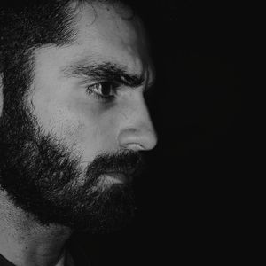 Side view of bearded man against black background