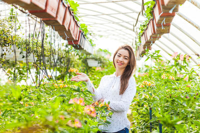 Portrait of smiling woman standing by plants