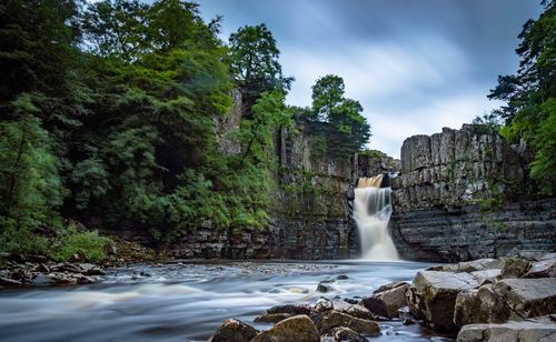 Scenic view of waterfall against sky