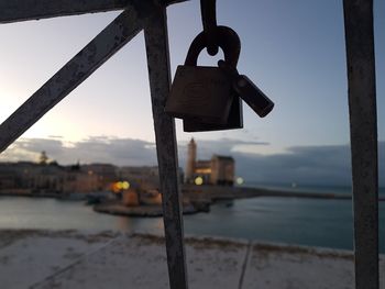 Close-up of padlocks hanging on rusty metal against sea