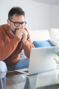 Young woman using laptop while sitting on sofa at home