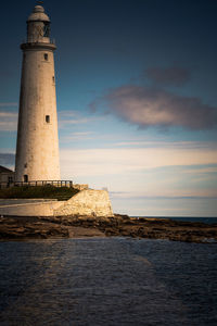 Lighthouse by sea against sky