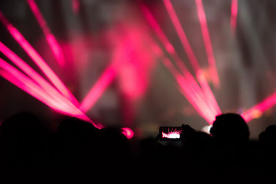 Silhouette people in illuminated music concert at night