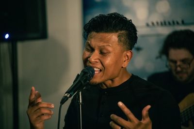 Mid adult man singing into a mic. 