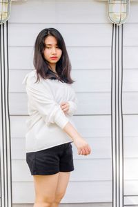 Young woman standing against wall