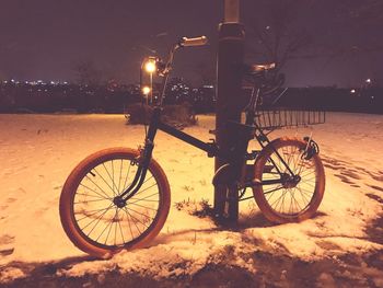 Bicycle parked on snow at night