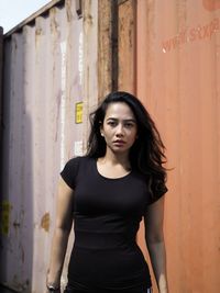 Portrait of beautiful young woman standing against wall