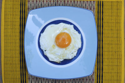 Directly above shot of sunny side up egg in blue plate