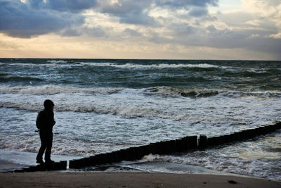 Silhouette people looking at sea against sky