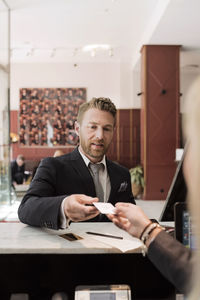 Businessman giving credit card to receptionist at hotel reception