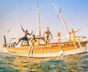 People with boats in sea against clear sky