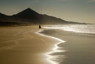 Silhouette person on beach against sky