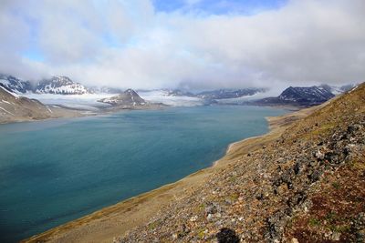 Scenic view of lake and mountains against cloudy sky