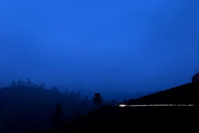 Scenic view of silhouette landscape against blue sky at night