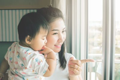 Close-up of mother and daughter looking through window