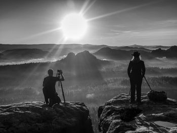 Two photographers discuss and share experiences. artists make photos on edge above daybreak land. bw