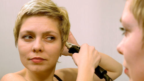 Close-up of woman holding equipment reflecting on mirror