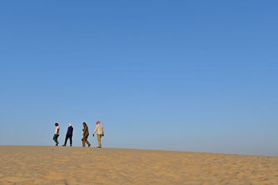 People walking on desert against sky