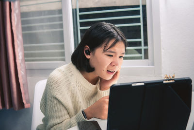 Portrait of a smiling young woman sitting at home