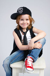 Portrait of a smiling girl sitting against wall