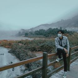 Man by railing against sky