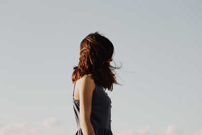 Side view of mature woman standing against sky