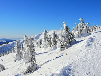 Scenic view of snow covered mountains against clear blue sky