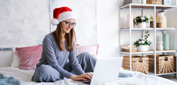 Woman in santa hat playing on laptop at christmas online shopping for holidays