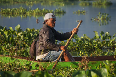 Side view of man sitting on grassy field