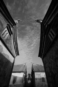 Low angle view of buildings against cloudy sky