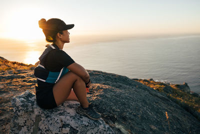 Side view of woman wearing cap looking at sea