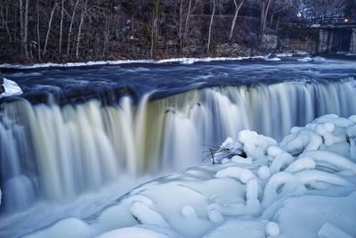 Frozen river against trees during winter