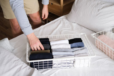 Closeup of hands of an man tidy up things in mesh storage containers. vertical storage of clothing.