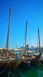 Sailboats moored at harbor against clear blue sky