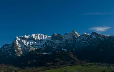 Scenic view of snowcapped mountains against blue sky