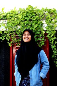 Portrait of smiling young woman standing against wall at house of sampoerna