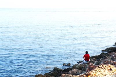 Rear view of man standing on rock in sea